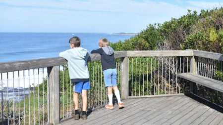 Two boys looking from a viewing platform out to the ocean, taken at Iluka Bluff Lookout