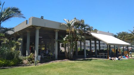 Building structure offering shade, green grass, sunny blue sky