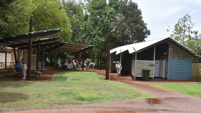 Grass park with sheltered picnic tables and a toilet block